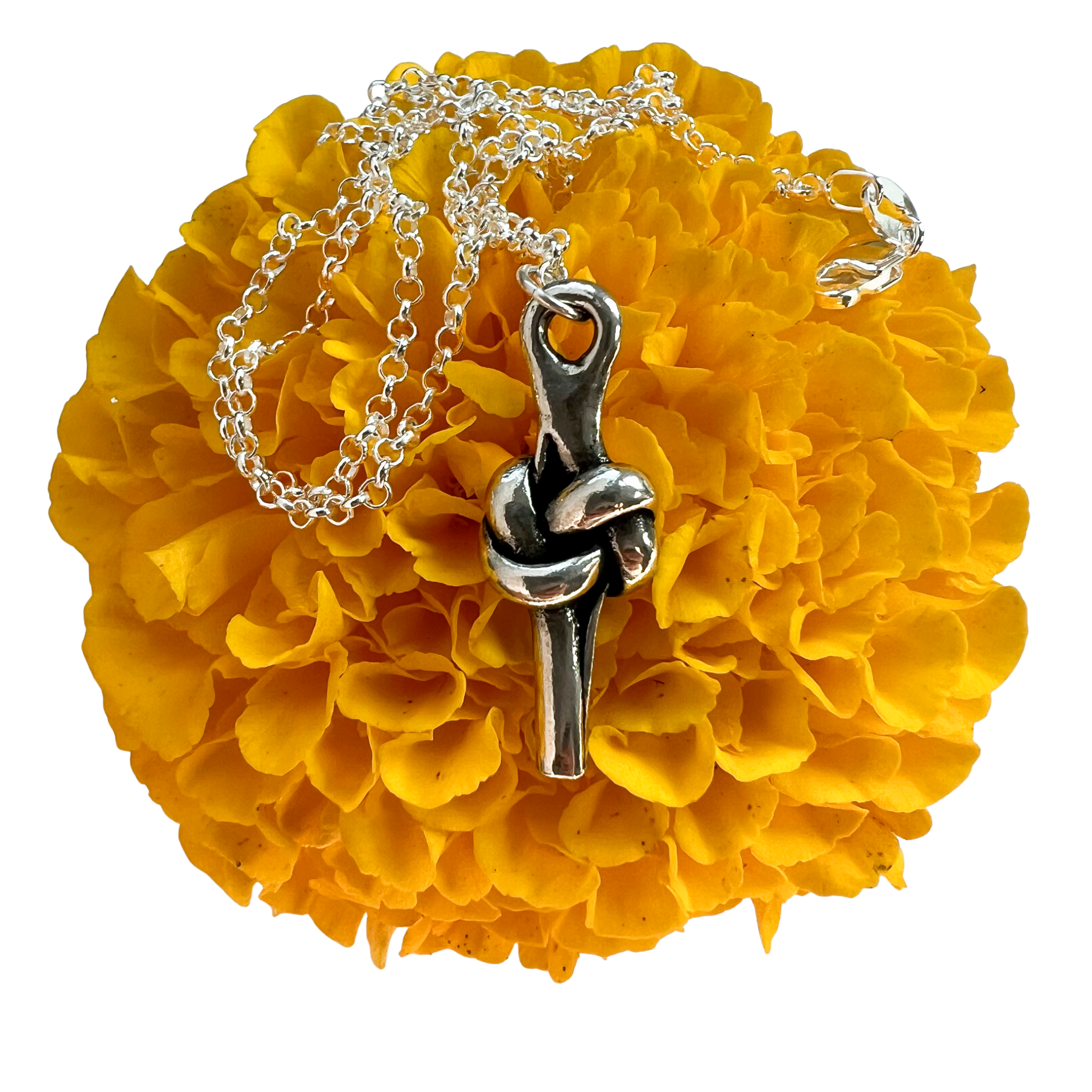 A silver necklace with a knot pendant, displayed on a bright yellow marigold flower against a white background.