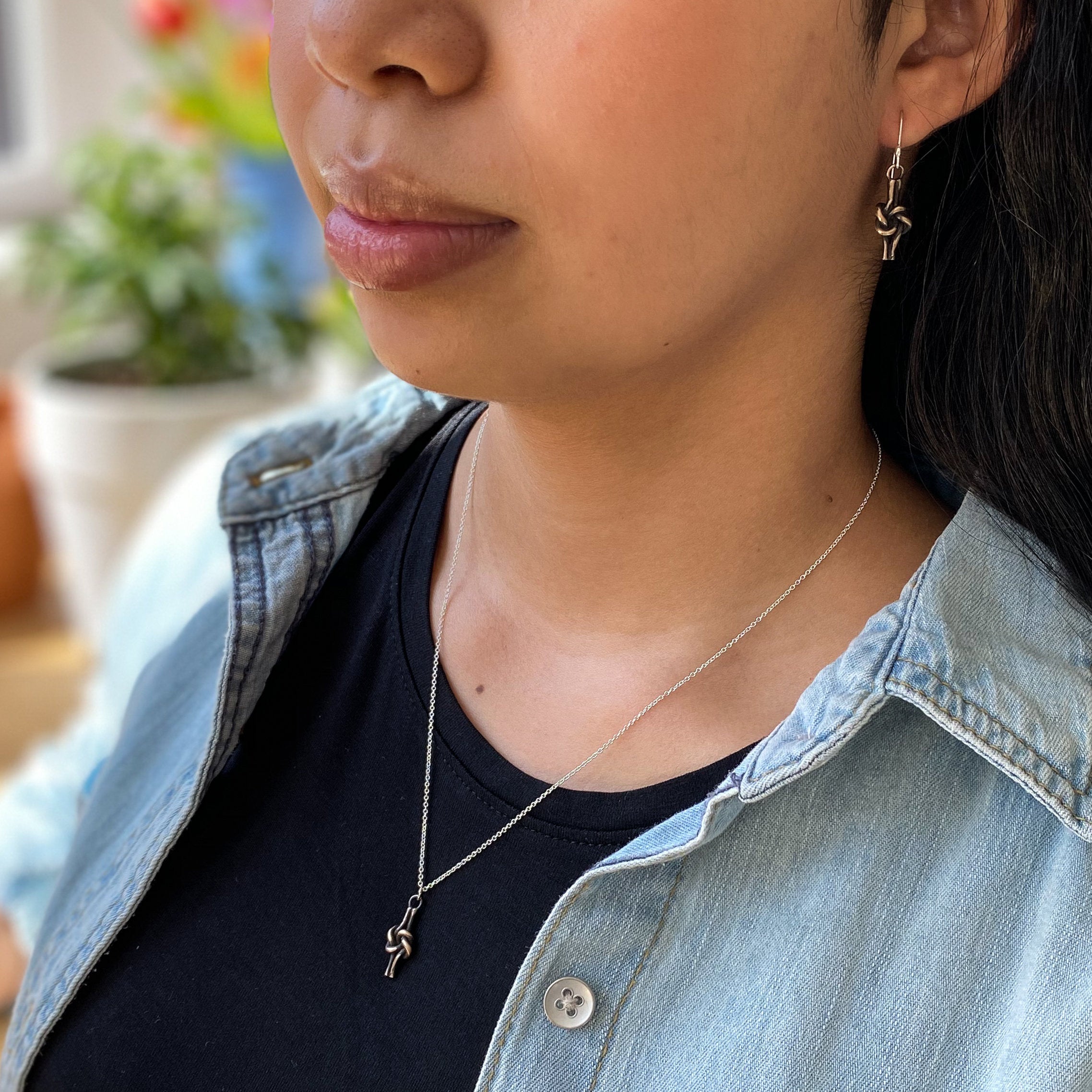 Bronze love knot jewelry set, delicate and pretty for everyday wear. Shown on a model with black t-shirt and denim shirt.