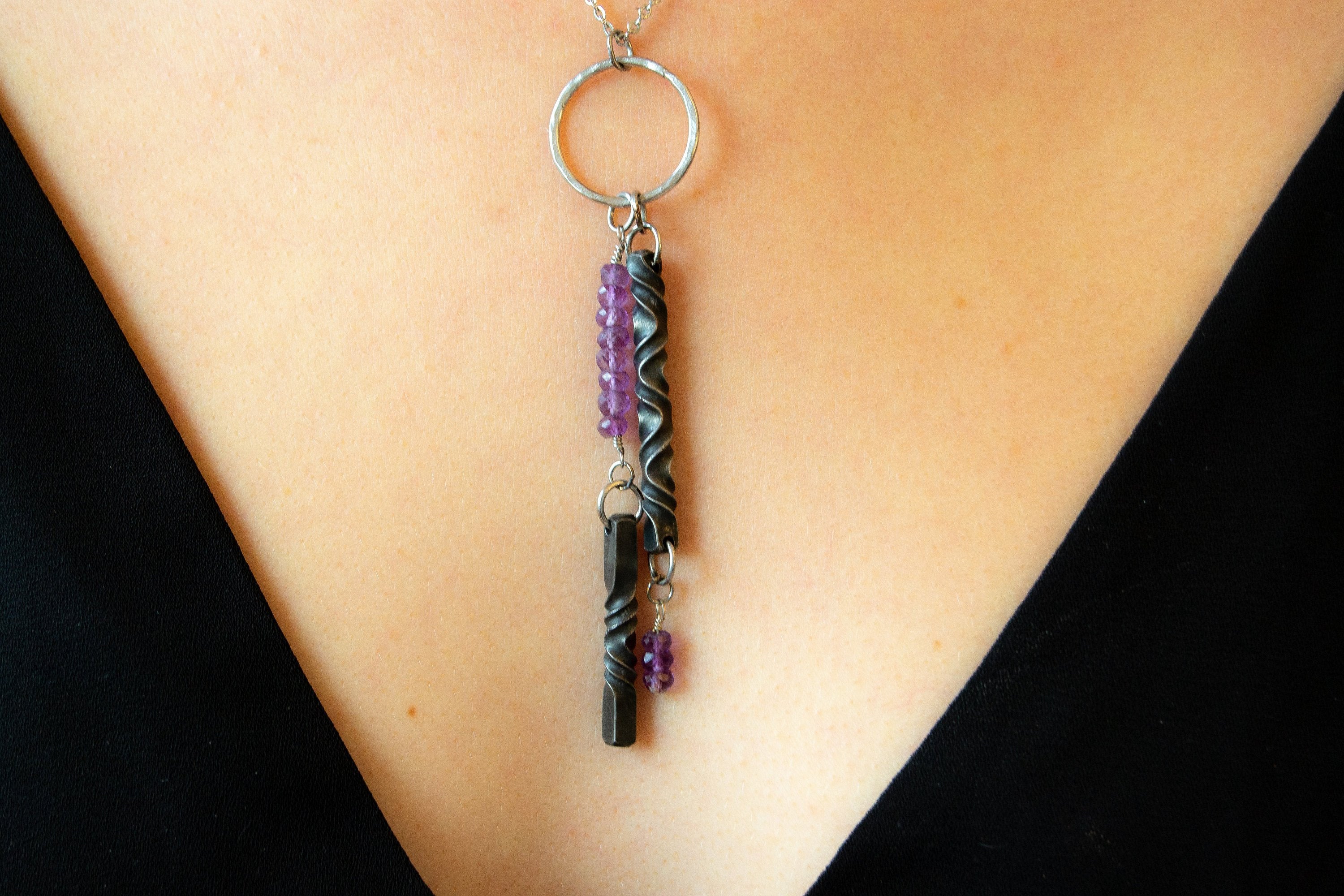 Iron and Amethyst necklace on model with black v neck shirt