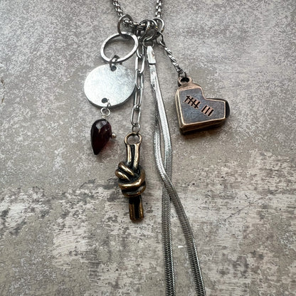 Necklace with bronze charms for 8th anniversary gift on gray plaster background.