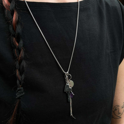 Person wearing a black t-shirt with a stainless chain featuring multiple charms for 6th anniversary gift.