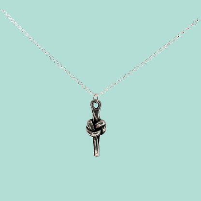 A silver chain necklace with a small pendant shaped like a love knot, shown on a solid light aqua background.