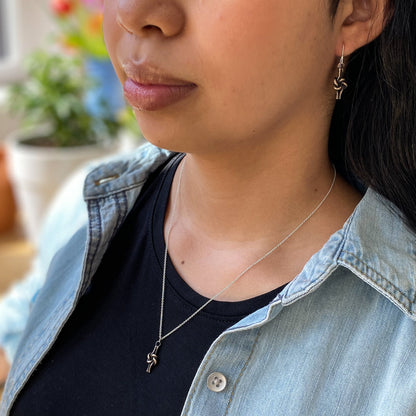 Bronze love knot jewelry set, delicate and pretty for everyday wear. Shown on a model with black t-shirt and denim shirt.