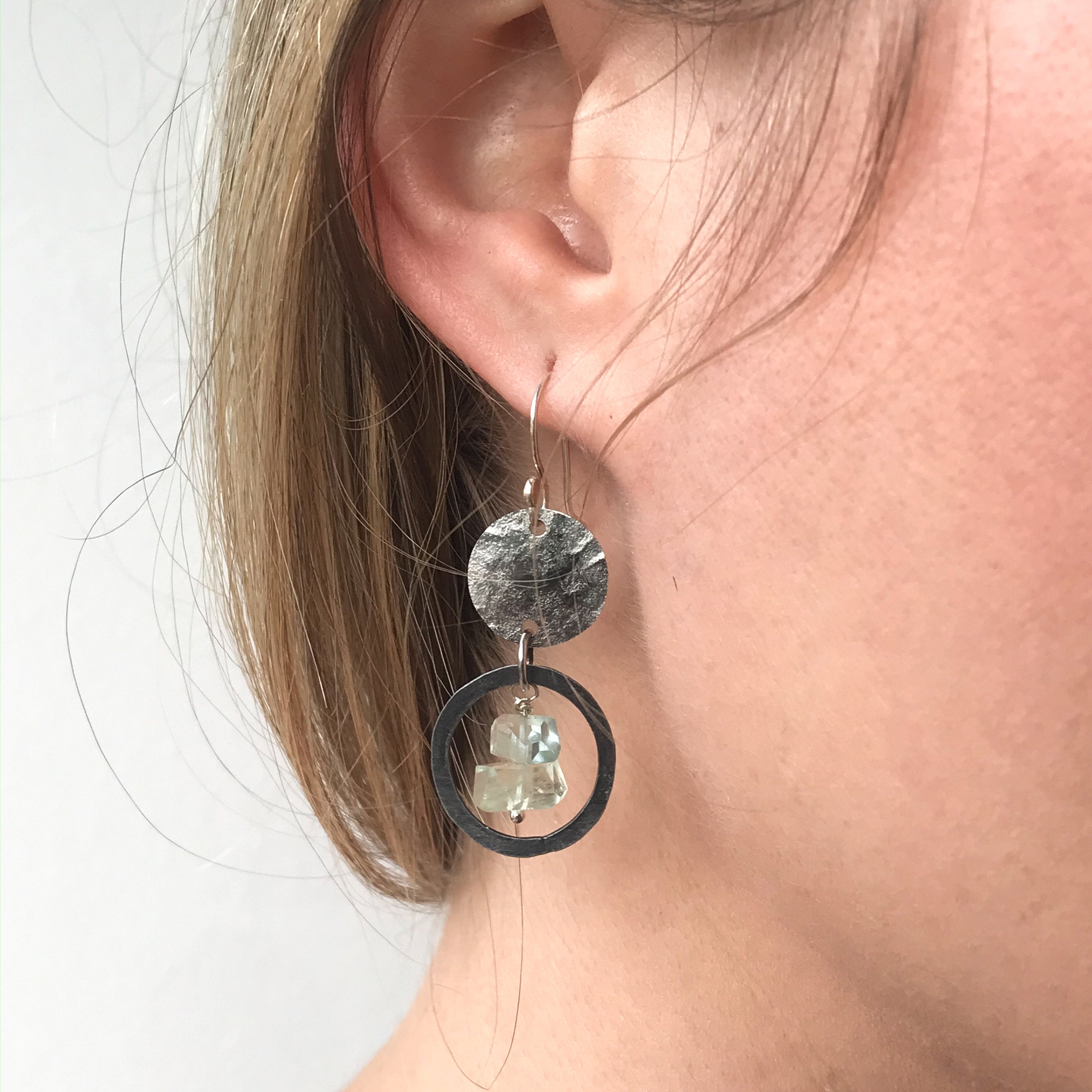 closeup of hand hamerred stainless steel earrings with aquamarine nugget beads on model's ear with bond hair
